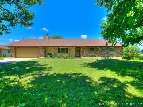 ranch-style house featuring an attached garage, a chimney, a front yard, and stone siding