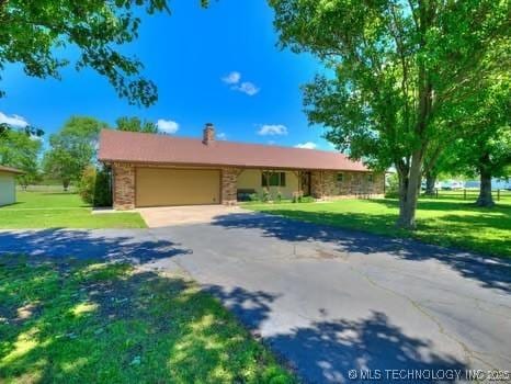 ranch-style home with a front yard, a chimney, a garage, and aphalt driveway