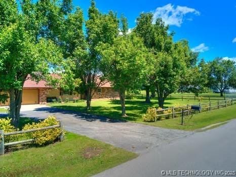 view of property's community featuring a yard, aphalt driveway, and fence