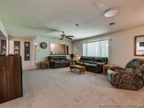 carpeted living room featuring a textured ceiling, visible vents, and ceiling fan