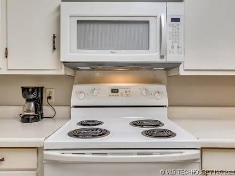 details with white cabinetry, white appliances, and light countertops