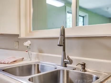 room details featuring light countertops, white cabinetry, and a sink