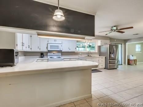 kitchen featuring a peninsula, white appliances, light tile patterned flooring, light countertops, and a ceiling fan