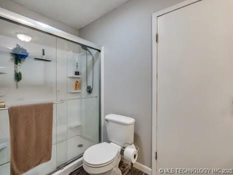 bathroom featuring toilet and a stall shower