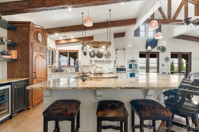 9639 Horizon Cir, Sperry, OK 74073 - kitchen with wine cooler, open shelves, beamed ceiling, and double oven
