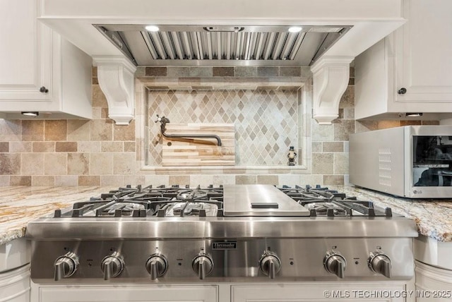 9639 Horizon Cir, Sperry, OK 74073 - kitchen with light stone counters, white cabinetry, backsplash, custom range hood, and appliances with stainless steel finishes