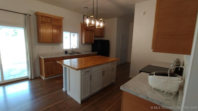 21316 County Road 502, Colcord, OK 74338 - kitchen featuring freestanding refrigerator, decorative light fixtures, dark wood-type flooring, a sink, and a kitchen island