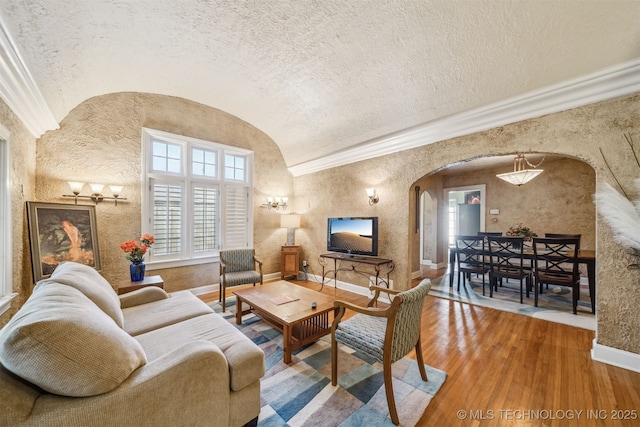 1731 S Florence Pl, Tulsa, OK 74104 - living room with baseboards, wood-type flooring, vaulted ceiling, arched walkways, and a textured wall