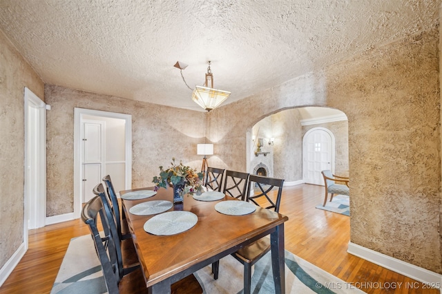 1731 S Florence Pl, Tulsa, OK 74104 - dining space featuring a textured ceiling, wood finished floors, baseboards, and arched walkways