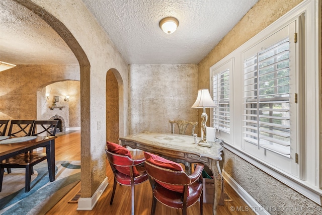 1731 S Florence Pl, Tulsa, OK 74104 - dining space with a textured ceiling, wood finished floors, arched walkways, and a textured wall