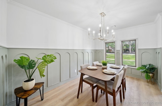 1402 E 125th St S, Jenks, OK 74037 - dining area featuring a decorative wall, a chandelier, light wood-type flooring, crown molding, and wainscoting