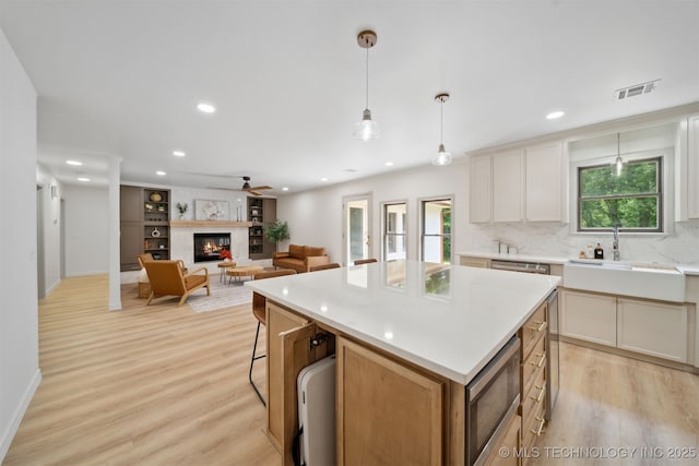 1402 E 125th St S, Jenks, OK 74037 - kitchen with a sink, stainless steel appliances, light wood finished floors, decorative backsplash, and a kitchen island