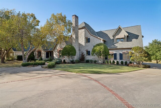 5263 Oak Leaf Dr, Tulsa, OK 74131 - french country home featuring a chimney, a front lawn, stone siding, and brick siding