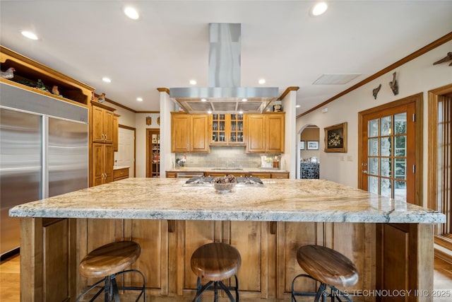 5263 Oak Leaf Dr, Tulsa, OK 74131 - kitchen featuring appliances with stainless steel finishes, island range hood, ornamental molding, arched walkways, and recessed lighting