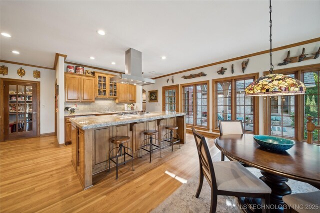 5263 Oak Leaf Dr, Tulsa, OK 74131 - kitchen with island exhaust hood, ornamental molding, a breakfast bar, a large island with sink, and light wood finished floors