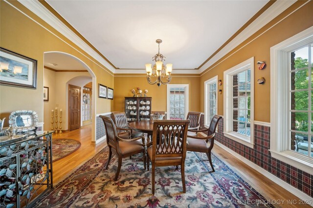 5263 Oak Leaf Dr, Tulsa, OK 74131 - dining space with arched walkways, wood finished floors, ornamental molding, plenty of natural light, and a chandelier