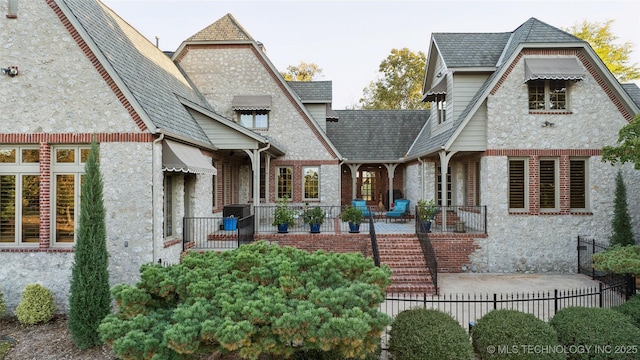 5263 Oak Leaf Dr, Tulsa, OK 74131 - view of front facade with fence, stone siding, and brick siding