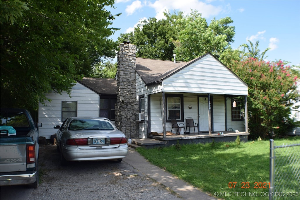 bungalow-style house featuring covered porch, a front yard, and a chimney
