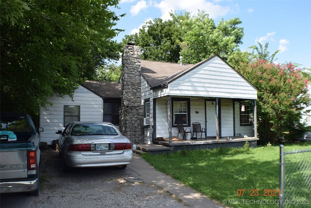 bungalow-style house featuring covered porch, a front yard, and a chimney