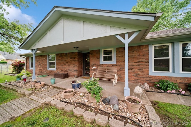 rear view of property featuring a patio area, brick siding, and fence