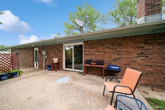 rear view of property with brick siding, a patio area, and a chimney