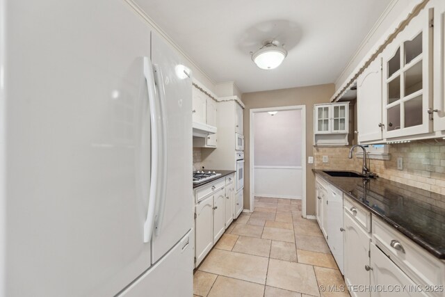 kitchen with white appliances, a sink, decorative backsplash, glass insert cabinets, and white cabinetry