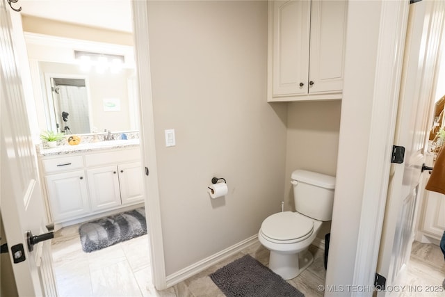 bathroom with toilet, vanity, and baseboards