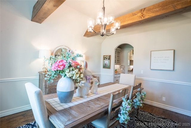 dining area featuring a chandelier, arched walkways, wood finished floors, and baseboards