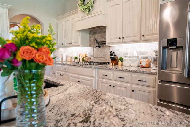 kitchen featuring appliances with stainless steel finishes, tasteful backsplash, light stone countertops, and white cabinetry