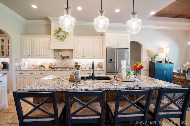 kitchen with appliances with stainless steel finishes, a sink, arched walkways, a kitchen bar, and recessed lighting