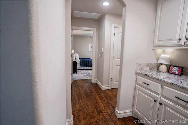corridor featuring dark wood-style flooring, arched walkways, and baseboards