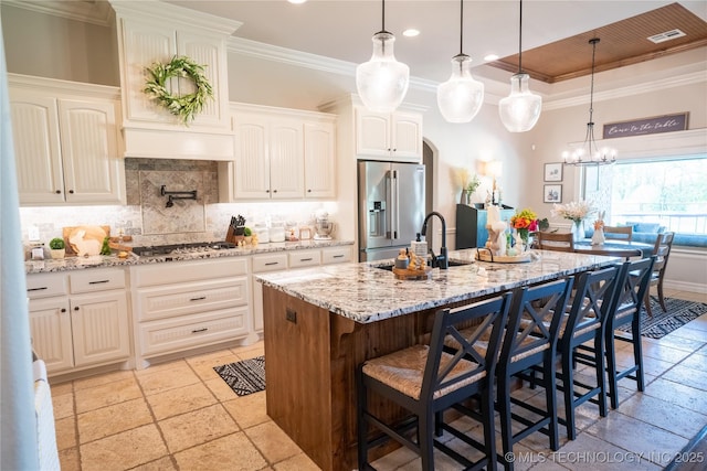 kitchen featuring appliances with stainless steel finishes, a sink, stone tile floors, decorative backsplash, and crown molding