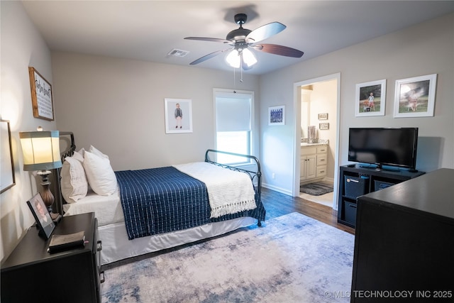 bedroom with wood finished floors, baseboards, ensuite bath, and a ceiling fan