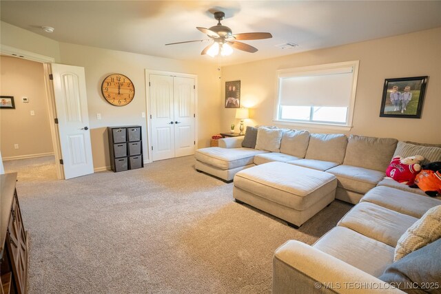 carpeted living area with a ceiling fan and baseboards