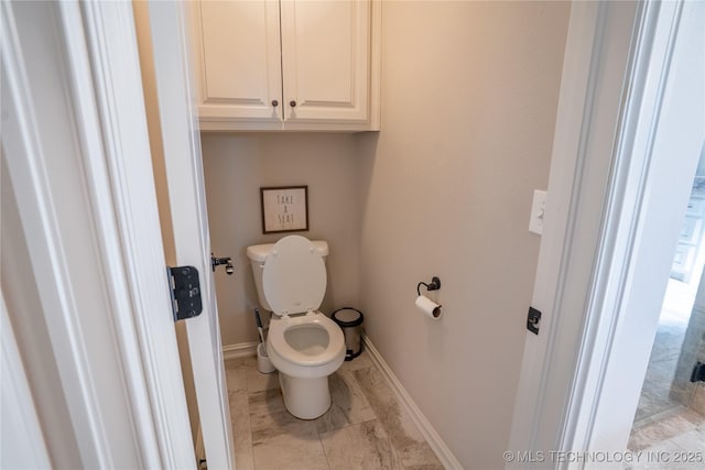 bathroom featuring baseboards, toilet, and marble finish flooring