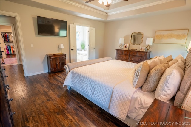 bedroom with ornamental molding, wood finished floors, baseboards, and a raised ceiling