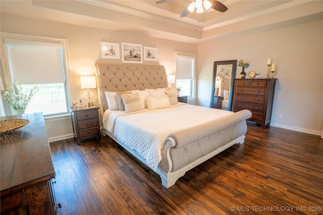 bedroom featuring a tray ceiling, dark wood-style floors, ornamental molding, baseboards, and ceiling fan