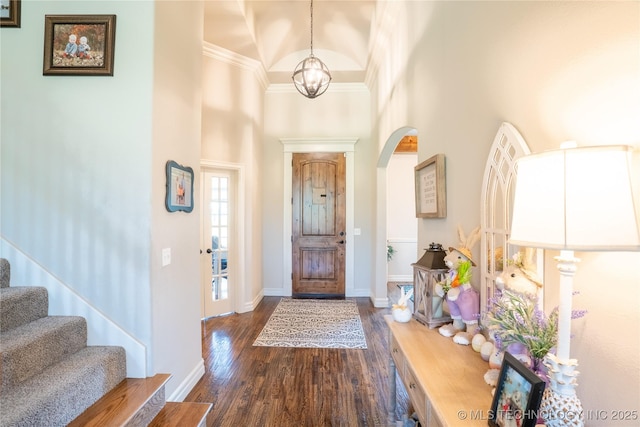 entrance foyer with a high ceiling, arched walkways, baseboards, a chandelier, and dark wood finished floors