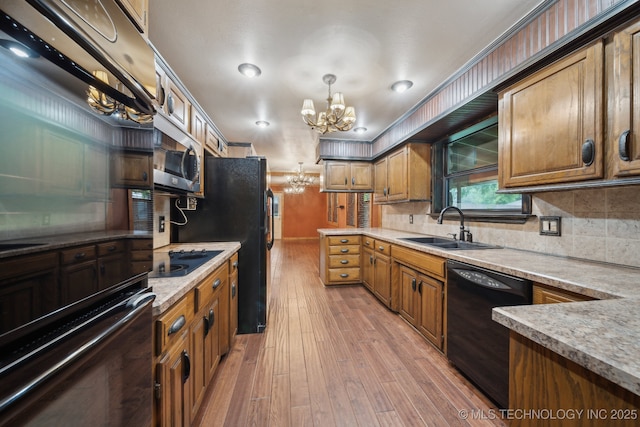 kitchen featuring black appliances, a chandelier, a sink, light wood-style floors, and brown cabinets