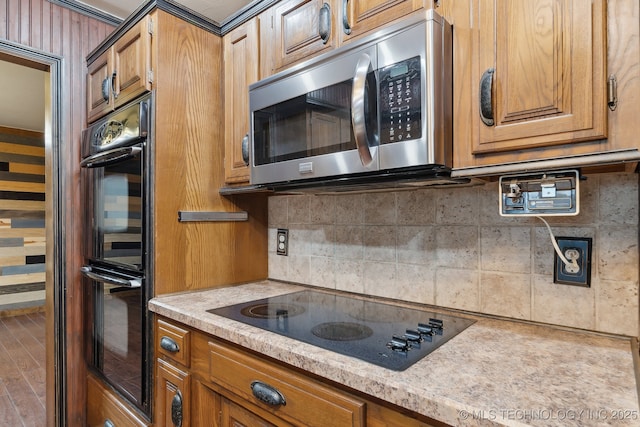 kitchen featuring black appliances, brown cabinets, wood finished floors, and decorative backsplash