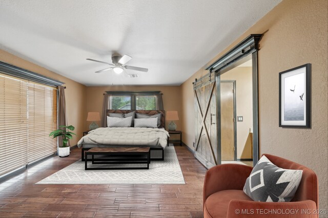 1405 W Huntsville St, Broken Arrow, OK 74011 - bedroom featuring a barn door, a textured wall, wood finished floors, and ceiling fan