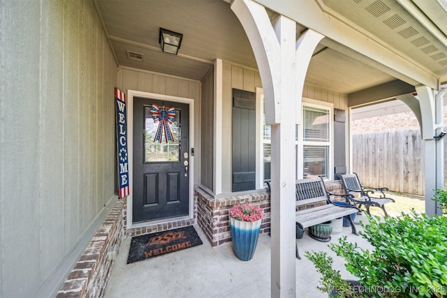 entrance to property featuring a porch and fence