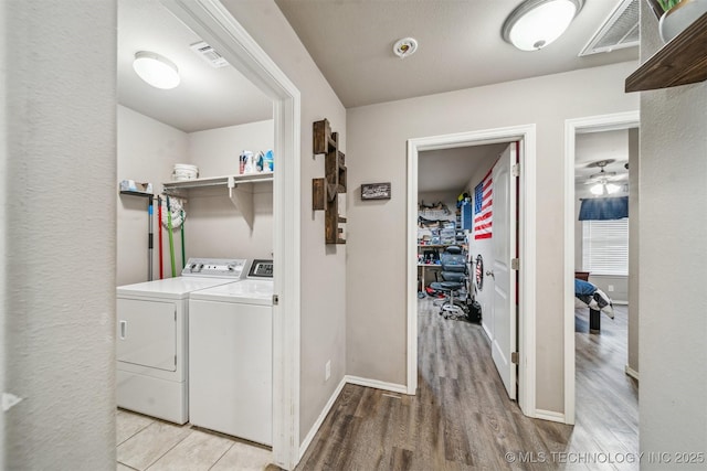 clothes washing area featuring washing machine and dryer, light wood finished floors, baseboards, and a ceiling fan