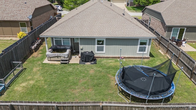 back of house featuring a trampoline and roof with shingles