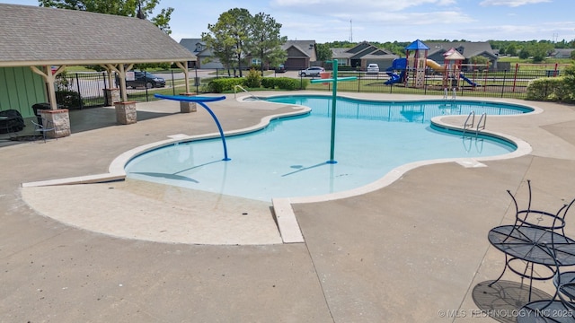 community pool featuring fence, a patio, and a residential view