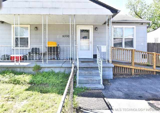 property entrance featuring a porch and roof with shingles