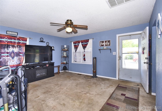 carpeted living area with a ceiling fan, a textured ceiling, and baseboards