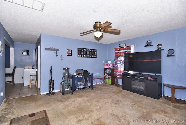 carpeted living area featuring ceiling fan, a textured ceiling, and baseboards