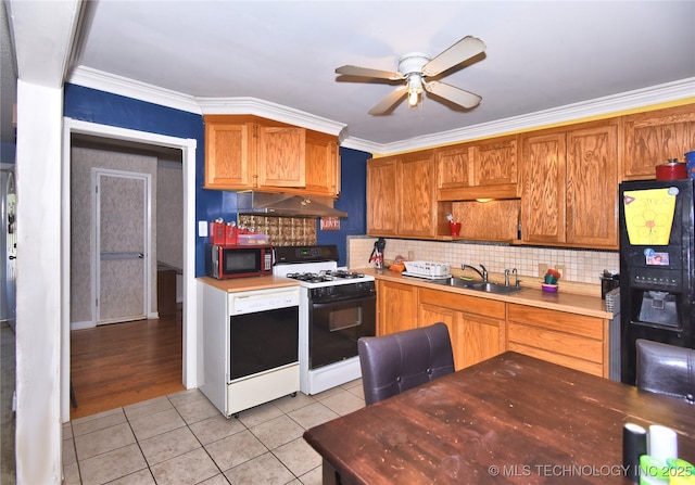 kitchen with gas stove, light tile patterned flooring, a sink, ceiling fan, and tasteful backsplash