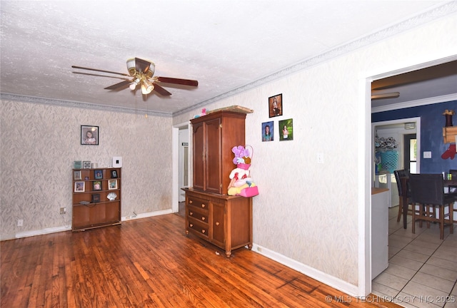 unfurnished room with a ceiling fan, wood finished floors, ornamental molding, and baseboards